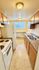Bright and cozy galley kitchen with modern fixtures, ample countertop space, and wooden cabinetry.