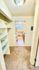 Inviting hallway leading to a bright kitchen with modern appliances and ample natural light, featuring stylish shelving and cozy carpeting.