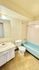 Bright and inviting bathroom featuring a sleek blue bathtub, modern sink with marble countertop, and stylish tile flooring.