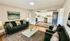 Inviting living room with elegant dark green sofas, chic coffee table, and open access to a modern, well-equipped kitchen.