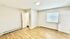 Bright and airy room with sleek wooden floors, modern white walls, and ample natural lighting from a large window with blinds.