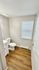 Bright and modern bathroom featuring sleek white fixtures and warm wood-style flooring.
