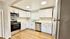 Modern kitchen with sleek stainless steel appliances, elegant white cabinets, and stylish wood flooring, offering a spacious and inviting cooking area.