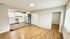 Bright open-concept living area with modern kitchen, featuring white cabinets, stainless steel appliances, and sleek hardwood flooring.