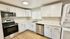 Modern kitchen with sleek stainless steel appliances, bright white cabinetry, and elegant marble countertops. Natural light fills the space, complementing the warm wood flooring.