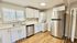 Bright modern kitchen featuring sleek stainless steel appliances, white cabinetry, and in-unit washer and dryer for convenience.