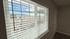 Bright and airy apartment view through large window blinds showcasing scenic mountain landscape.