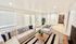 Bright and inviting living room with cozy white sofas, stylish striped cushions, and a chic wooden coffee table adorned with plants, leading to a tiled entryway with built-in shelves.