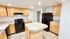 Modern kitchen with sleek black appliances, ample wooden cabinetry, and a spacious tiled countertop island.