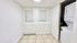 Bright laundry nook with stacked washer and dryer, tiled flooring, and two windows with blinds.