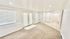 Bright and airy living space with plush carpeting and double doors leading outside, enhanced by recessed lighting and tiled entryway.