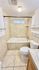 Bright bathroom featuring a soaking tub, tile accents, and ample storage for a modern living experience.