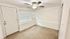 Bright and cozy room with carpet flooring, ceiling fan, and large windows for natural light.