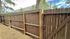 Charming wooden fence with natural surroundings, pine trees, and a glimpse of modern apartments in the background.