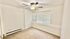 Bright, cozy room with neutral carpeting, large window with blinds, and ceiling fan, perfect for a relaxing retreat.