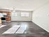 Bright and spacious open-concept living area with modern wood flooring and kitchen featuring stainless steel appliances.