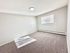 Spacious and bright empty room with plush carpeting, neutral walls, and a large window offering ample natural light.