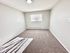 Bright, freshly painted room with plush carpet and natural light from a large window, perfect for relaxation.