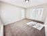 Bright and spacious bedroom with plush carpet, neutral walls, and ample closet space.