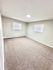 Bright and spacious bedroom with plush carpet and large windows, ideal for comfort and relaxation.