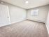 Bright, spacious bedroom with plush carpeting, modern white walls, and ample natural light.