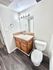 Modern bathroom featuring elegant lighting, sleek wooden vanity, and pristine ceramic fixtures.
