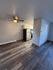 Modern apartment kitchen with sleek appliances, wood flooring, and a ceiling fan creating a cozy and inviting atmosphere.