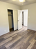 Bright and spacious bedroom featuring sleek wood flooring, modern closet doors, and ample storage space.