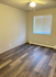 Bright and inviting room with modern wood flooring, large window, and ceiling fan creating a cozy ambiance.