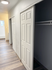 Modern hallway with elegant closet doors and sleek laminate flooring leading to a bright bathroom.
