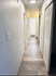 Bright corridor with modern wood flooring and well-lit interior leading to a bathroom, showcasing spacious, contemporary apartment design.