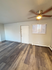 Bright open living room with modern wood flooring, ceiling fan, and large window for natural light.