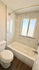 Elegant bathroom with a modern soaking tub, sleek marble tiling, and a large window for natural light.