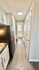 Bright and welcoming kitchen corridor with modern black appliances and stylish white cabinetry, leading to a sunlit space.