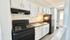 Contemporary galley kitchen with elegant black appliances, sleek white cabinetry, and modern fixtures.