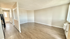 Bright and spacious living area with elegant wooden flooring and ample natural light, adjacent to sleek hallway leading to bathroom.