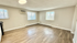 Bright and spacious living room with modern wooden flooring, large windows offering natural light, and efficient air conditioning.