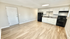 Bright and inviting open-plan kitchen with sleek white cabinets, modern appliances, and elegant hardwood flooring.