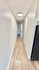 Bright hallway with modern lighting and elegant wood flooring leading to spacious living areas.