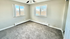 Bright corner room featuring large windows and soft carpet, offering a serene view and cozy ambiance.