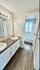 Elegant bathroom with dual sinks, a large mirror, and a bright, airy atmosphere featuring modern fixtures and wood flooring.
