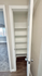 Chic apartment linen closet with built-in shelves, modern door handle, and cozy carpeted bedroom view.