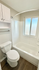 Bright modern bathroom with a sleek white tub, elegant white cabinetry, and a large frosted window.