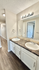 Chic bathroom with dual sinks, elegant lighting, and stylish countertops, leading to a bright hallway.