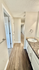 Bright and modern hallway with elegant wood flooring and a contemporary bathroom featuring sleek granite countertops.