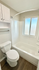Bright bathroom featuring a sleek bathtub, modern white cabinetry, and a large window for natural light.