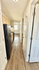 Inviting apartment hallway featuring sleek hardwood floors, a modern black refrigerator, and ample natural light.
