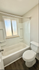 Bright and inviting bathroom with a modern bathtub and elegant wooden flooring, perfect for relaxation.