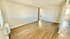 Bright and airy living room with elegant wood flooring and neutral wall tones, leading to a cozy bedroom space.
