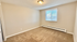 Bright, spacious bedroom with plush carpet and large window, perfect for relaxation and comfort.
